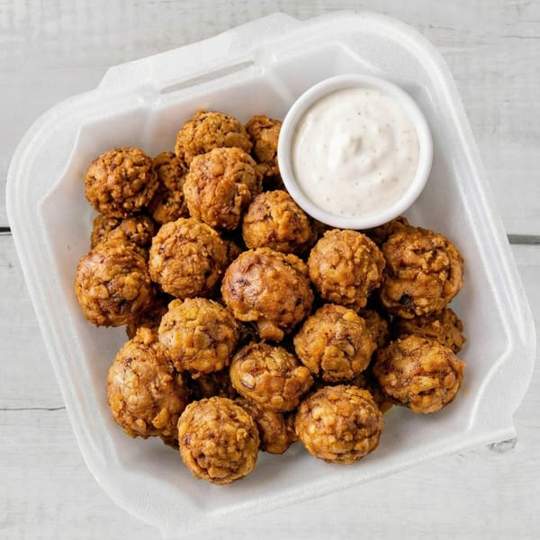 Crispy fried mushrooms and a side of ranch dressing in a white takeout container.